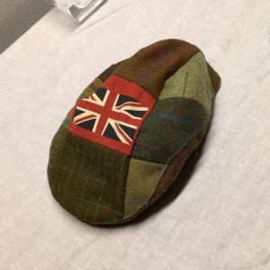 Klassisk Rutig basker keps från Timothy Foxx - Snygg rutig keps från Timothy Foxx med Union Jack-detalj. Kepsen har en patchwork-design i gröna och bruna nyanser med inslag av rött och blått. Perfekt för en unik och stilren look. 