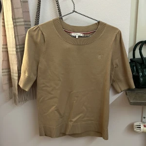 Beige tröja från Tommy Hilfiger - Säljer en jätte skön och stilren tajt stickad tröja från Tommy Hilfiger i storlek S. Den ser helt ny ut och har nästan aldrig användas, säljer då den inte kommer till användning💕