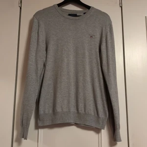 Tröja från GANT - Säljer en stilren grå tröja från GANT med broderad logga på bröstet. Tröjan har långa ärmar och ribbade muddar vid ärmslut och nederkant. Perfekt för en avslappnad look. Knappt använd och den har inga defekter. Perfekt för Jul och Nyår🤩 Passar främst killar men funkar för tjejer också. Skriv vid frågor 🤩