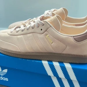 Beige Adidas Samba OG sneakers - Snygga beige Adidas Samba sneakers med klassisk design och snörning. Perfekta för en stilren look. Aldrig använda. Kartongen har lite skador. 