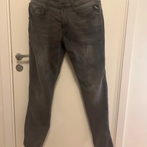 Grå jeans från Replay - Snygga grå jeans från Replay, modell Anbass. De har en klassisk femficksdesign och en knappgylf. Perfekta för en stilren look.