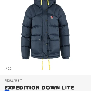 SÖKER!!! fjällräven jacka - Snygg och varm dunjacka från Fjällräven med regular fit. Jackan har en klassisk design med gula detaljer och praktiska fickor. Perfekt för kalla dagar.