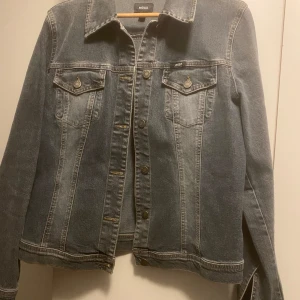 Grå jeansjacka från Mexx - Snygg grå jeansjacka från Mexx med klassisk design. Jackan har långa ärmar och knappar framtill samt två bröstfickor med knappstängning. Perfekt för en avslappnad stil.