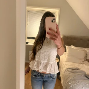 Vit ärmlös blus - Säljer en söt vit blus med spetsdetaljer och volang nedtill. Blusen är ärmlös och perfekt för varmare dagar. Passar bra till jeans eller kjol❤️