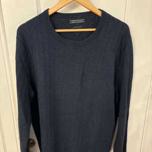 Mörkblå tröja från Tommy Hilfiger - Säljer en stilren mörkblå tröja från Tommy Hilfiger i Pima Cotton Cashmere. Tröjan har en klassisk rund hals och långa ärmar, perfekt för en elegant och bekväm look.
