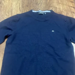 Mörkblå merinoull tröja från j lindeberg - Säljer en stilren mörkblå merinoull tröja från J.Lindeberg. Tröjan har en liten logotyp på bröstet och rund halsringning. Perfekt för en avslappnad men ändå snygg look. Står XS men sitter som typ nånting mellan 160-170.                                              Priset ej hugget i sten.