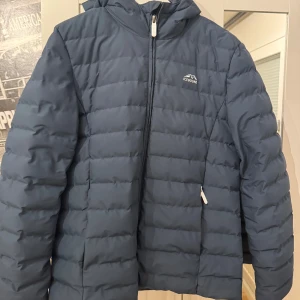 Blå quiltad jacka från Icebound Storlek M - Säljer en blå quiltad jacka från Icebound med dragkedja och huva. Perfekt för kyliga dagar med sin pufferdesign som håller värmen. Jackan har en stilren look och är lätt att matcha med olika outfits.Strl M