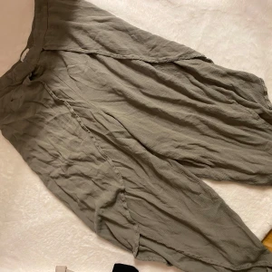 Grå byxor från Kappahl - Säljer ett par gröna byxor från Kappahl i storlek M. Byxorna har en loose passform och är tillverkade i ett lätt och luftigt material, byxkloj