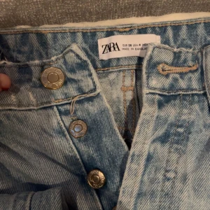 Ljusa jeans från Zara - Säljer ett par ljusa jeans från Zara med knappgylf och klassisk femficksdesign. Perfekta för en avslappnad stil.