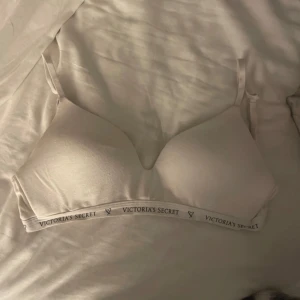Vit bh från Victoria's Secret - Säljer en vit bh från Victoria's Secret med justerbara axelband och mjuka kupor. Den har en elastisk kant med logotypen för extra komfort och stil. Perfekt för vardagsbruk.
