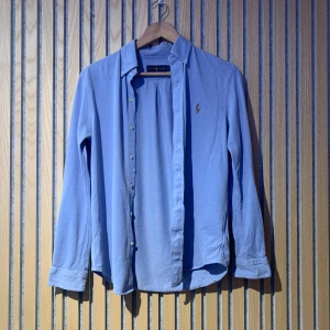 Polo Ralph Lauren skjorta - En polo Ralph Lauren skjorta i färgen ljusblå storleken är smal och den passar väldigt snyggt på dig som ska på fest eller liknande. Den har sju knappar och sitter stilrent och snyggt. Kan diskutera priset om hundring inte är något överdrivet riktigt snygg kostar typ 1300 ny. Inga defekter. Endast ett litet lagat hål