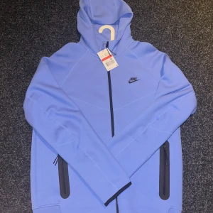 Blå hoodie från Nike - Säljer en blå hoodie från Nike. Fick den i födelsedagspresent men det är inte min stil. Kunde inte sicka tillbaka då det var försent. Har aldrig använt den hängt i min garderob i ca 1månad. Original priset är 130€ vilket är 1 499kr men säljer den endast för 899kr. Den ör i storlek L