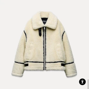 Beige teddyjacka från Zara - Säljer en mysig beige teddyjacka från Zara med svarta detaljer. Jackan har en dragkedja framtill och en klassisk krage. 