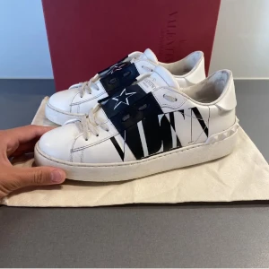 Valentino Open sneakers i vitt och svart - Säljer nu mina görr Snygga Valentino Open skor i vitt med svart och stjärn detalj. Köpta för ett år sedan och därav gammla ägarens bilder. Allt med följer på bilden ( kort, dustbag och kartong) har egna bilder