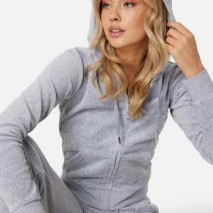 Grå hoodie och bootcut byxor från Juicy Couture - Säljer en stilren grå hoodie och bootcut byxor från Juicy Couture med dragkedja och huva. Tröjan har långa ärmar och en praktisk känguruficka framtill. Perfekt för en avslappnad look. Byxorna är bootcut med en glittrig loga på sida med back och fram fickor.