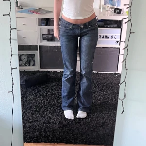 Blå jeans med låg midja - Säljer ett par snygga vintage jeans. De är bootcut och lågmidjade De är i väldigt bra skick! Snygga detaljer på bakfickorna och dubbla knappar. Är i storlek W27 L 34, men skulle söga att de passar xs/s.