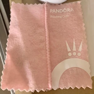 Pandora armband med berlock - Har ett armband från Pandoras 100års jubileum från Disney. En berlock ingår i köpet. Skickas även med en rengöringstrasa och rengöringsmedel från Pandora.. armbandet kostade nästan 2000 och berlocken 1600kr. Sen även putsduk och rengöringsmedel med