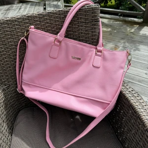 Rosa stor väska 🎀 - Säljer en superfin rosa väska. Den är i syntetmaterial och har en praktisk dragkedja upptill. Insidan är randig och har flera fack för bra organisering. Perfekt storlek för laptop, skolböcker mm. Hämtas på Hägerstensåsen eller ök. 🌸🩷🎀