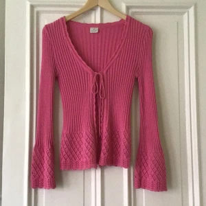 Rosa ribbad tröja från Mentor - Säljer en superfin rosa ribbad tröja från Mentor. Den har en v-ringad design med knytning framtill och långa ärmar. Tröjan har också ett snyggt mönster längst ner på ärmarna och nederkanten. Perfekt för både vardag och fest!