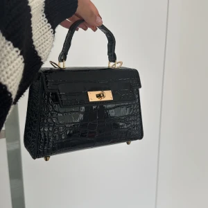 Svart väska  - Svart väska som passar bra med mycket. (Band till väskan ingår)