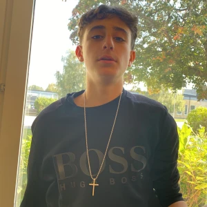 Svart tröja från Hugo Boss - Säljer en snygg svart tröja från Hugo Boss. Den har en stilren design med deras logga tryckt på framsidan. Perfekt för både vardag och lite finare tillfällen. Tröjan har långa ärmar och en normal passform. Passar perfekt till jeans eller chinos!