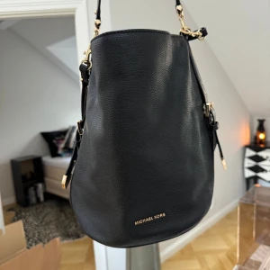 Michael Kors väska - Så snygg Michael Kors väska som är svart med gulddetaljer. Har både kort handtag och en axelrem.
