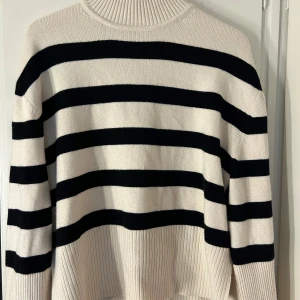 Randig stickad tröja - Säljer en supermysig randig tröja i svart och vit. Den är stickad och har en normal passform med långa ärmar. Tröjan har en ribbad krage och slittar på sidorna.