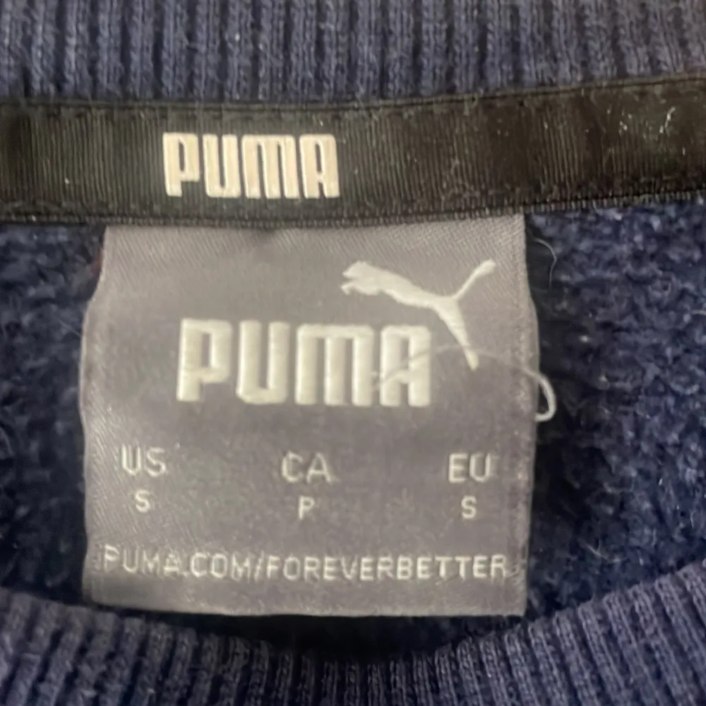 Säljer en snygg och bekväm mörkblå tröja från Puma. Den har en klassisk design med rund hals och långa ärmar. Perfekt för både vardag och träning. Tröjan är i bra skick och redo för en ny ägare!. Tröjor & Koftor.