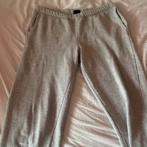 Grå mjukisbyxor från Gina Tricot - Säljer ett par superbekväma grå mjukisbyxor från Gina Tricot. Perfekta för en chill dag hemma eller en snabb tur till affären. De har en elastisk midja och två praktiska sidofickor. Materialet är mjukt och skönt, ops resorbandet i midjan är lite löst