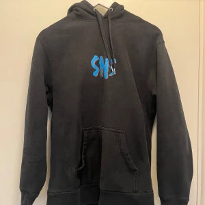 SNS Hoodie - Säljer just nu denna sjukt snygga hoodien från Sneakersnstuff i bra skick. Köpt för ett par år sedan runt 1000kr . Trycket på ryggen samt bröstet är litet uttvättat. Men annars är den i bra skick, inga hål eller liknande. Hör av dig vid frågor.