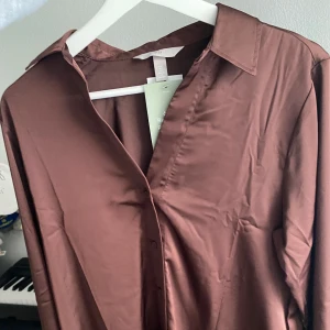 Satinblus - Säljer en helt ny oanvänd satinblus då den inte är min stil och då jag ska flytta och håller på rensa. Köptes i våras men har inte kommit till användning. Nypris 199kr (se bild) och storlek S. Skriv för fler bilder!