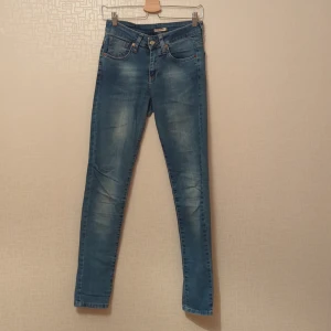 Blå jeans från Levi's - Säljer ett par snygga blå jeans från Levi's. De har en klassisk femficksdesign och är i en ljusblå tvätt. Perfekta för vardagsbruk och kan enkelt matchas med olika outfits. Dem har ett litet hål vid backfickan se bild, men kan absolut lagas av dig. 