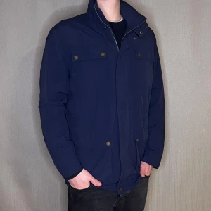 Field jacka storlek M  - Fieldjacka från Club Room 🧥🔧 Storlek: M Färg: Marinblå 🌊 OBS! Saknar en knapp vid magen, men en enkel fix 💡 Modellen på bilden är 183 cm och väger 75 kg.