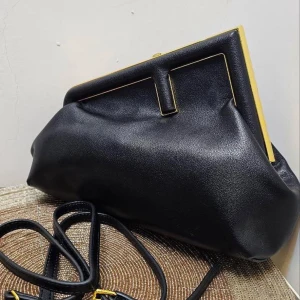 Svart axelväska från Fendi - Elegant svart axelväska från Fendi med gulddetaljer och ett stilrent geometriskt mönster på insidan. Väskan har en justerbar axelrem och en praktisk stängning med guldfärgad ram. Perfekt för att ge en lyxig touch till din outfit.