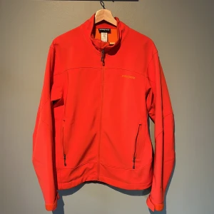 Orange softshell jacka från Patagonia - Säljer en orange softshell jacka från Patagonia med dragkedja och två fickor framtill. Jackan har en stilren design med långärmade ärmar och är perfekt för kyligare dagar. Den är tillverkad i polyester och har en bekväm passform. Jackan är i storlek M och är i använt skick. Lite smuts som går bort i tvätten. Pris går att diskuteras😁