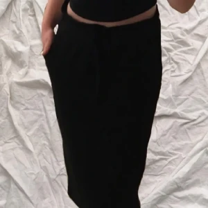 Svart kjol med knytband - Snygg svart kjol med knytband i midjan. Kjolen har en bekväm passform och praktiska fickor på sidorna. Perfekt för en stilren look.