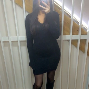 Svart stickad klänning - Snygg svart stickad klänning med lång ärm och v-ringning. Perfekt för kyligare dagar och kan stylas med olika accessoarer för en personlig touch.