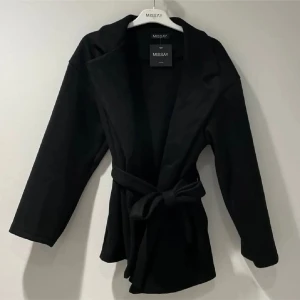 Svart kappa från Missay - Snygg svart kappa från Missay med knytband i midjan. Liten i storleken, korta ärmar. Kappan är lite nopprig men annars bra kvalitet. (Inte mina bilder)