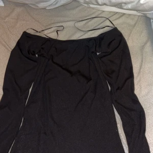 Svart offshoulder tröja - Elegant svart offshoulder tröja  från Amisu med långa ärmar och fjäderdetaljer vid ärmsluten. Perfekt för en stilfull kvällslook. passar mer som xs.