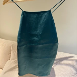 Gröt linne från NA-KD - Snygg grönt linne från Mathilde Gøhler x NA-KD med tunna axelband och en elegant, slät yta. Perfekt för en stilren look. 