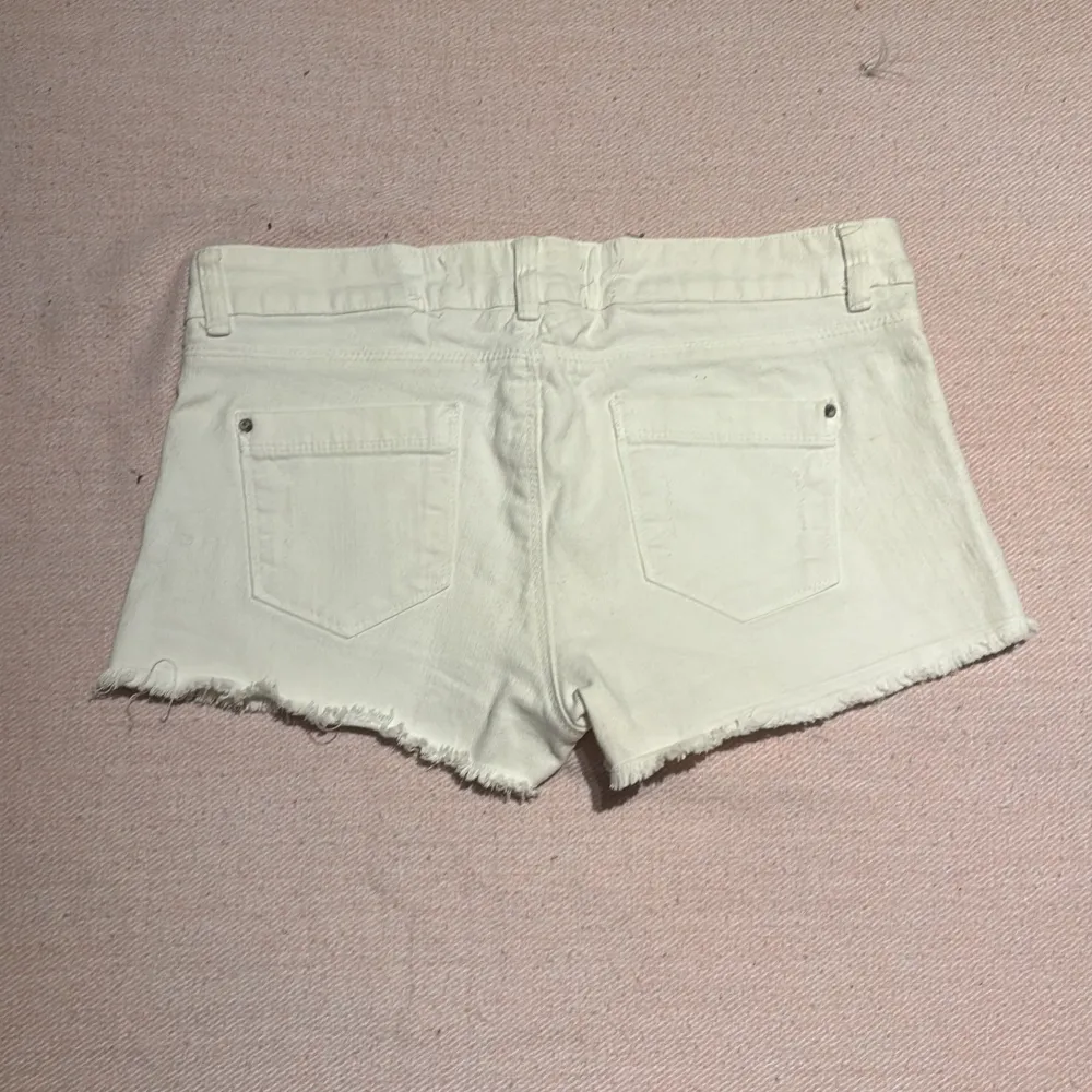 Snygga vita shorts från Bershka med fransiga kanter och nitar vid fickorna. De har en klassisk femficksdesign och knappgylf. Knappt använda och i väldigt bra skick!🌺. Shortsit.