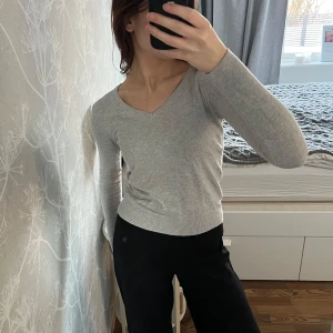 Grå v-ringad tröja - Säljer en grå v-ringad tröja med långa ärmar. Tröjan har en ribbad kant vid ärmslut och nederkant🤗