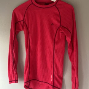 Röd långärmad tröja från North Bend - Säljer en röd långärmad tröja från North Bend i 100% polyester. Tröjan har lila sömmar som ger en sportig look. Säljer även matchande underställsbyxor. Perfekt för kyligare dagar eller som lager under jackan. Passar bra för utomhusaktiviteter. 