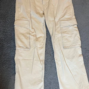 Beige cargobyxor - Snygga beige cargobyxor med flera praktiska fickor. Byxorna har en loose passform och är tillverkade i ett slitstarkt material. 