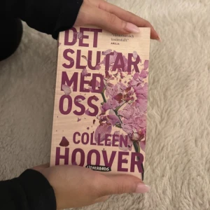 Det slutar med oss - Boken 'Det slutar med oss' av Colleen Hoover är en gripande roman som utforskar kärlekens komplexitet och utmaningar. Omslaget pryds av en vacker illustration av krossade blommor i lila nyanser, vilket speglar bokens emotionella djup.