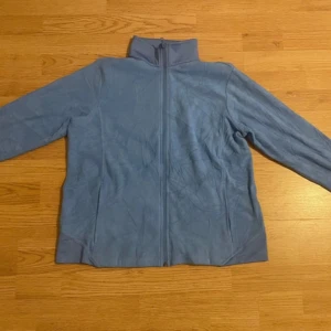 Blå fleecejacka från Lands' End - Säljer en mjuk och bekväm blå fleecejacka från Lands' End. Jackan har en dragkedja framtill och långa ärmar. Perfekt för kyliga dagar när du vill hålla dig varm och stilren.