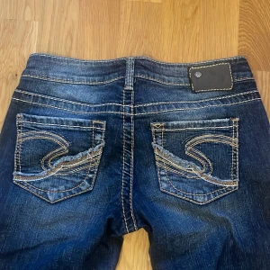 Snygga lågmidjade y2k bootcut jeans med kontrastsömmar - Snygga lowwaist y2k mörkblå bootcut jeans med coola kontrastsömmar och slitna detaljer på bakfickorna. Storlek W27💋
