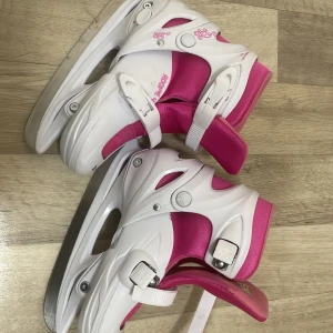 Vita och rosa skridskor - Säljer ett par justerbara vita och rosa skridskor med spännen för enkel justering. Perfekta för vinterns isäventyr. De har en bekväm passform och är designade för att ge bra stöd och stabilitet. Storleken är 34-37.