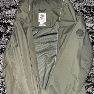 Timberland jacka i toppskick Storlek M, vattentät  - Säljer en grön Timberland-jacka i storlek M. Jackan är vattentät (waterproof) och perfekt för både vår och höst. Modern och stilren design med bra passform. Använd få gånger och i mycket fint skick, inga fläckar eller skador. Passar både till vardags och för utomhusaktiviteter. Säljes på grund av att den inte kommer till användning längre. Möjlighet till snabb affär! Passar ej mig 