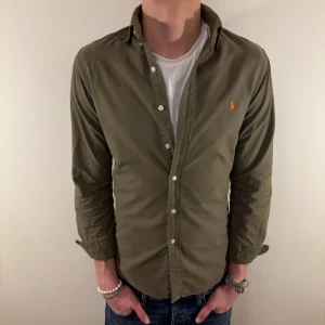 Grön Ralph Lauren skjorta - Nu säljer vi ännu en fet polo skjorta som passar till alla tillställningar, skjortan är i bra skick men har en tydlig blekning längs kragen som syns på sista bilden! Passa på, riktigt bra pris!🕺🍾💼🤩  Storlek👔:  S Nypris💰:  ca 1499 kr